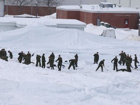 Canadian Forces personnel shovel snow off the dome at the Royal Military College of Canada on Wednesday. The dome was intentionally deflated to avoid it collapsing under the weight of the snow that fell on Tuesday. (Elliot Ferguson/The Whig-Standard)