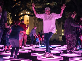 This Dec. 3, 2015 photo provided by Arts Council New Orleans shows people interacting with “The Pool,” a work that was part of New Orleans’ LUNA Fete light festival. The work, by artist Jen Lewin, is also going to be on display at Light City Baltimore, a light festival taking place in Baltimore March 28-April 3. Light festivals that combine contemporary art and technology, often with interactive features, are taking off as a trend. (Marcus Carter/Arts Council New Orleans via AP)