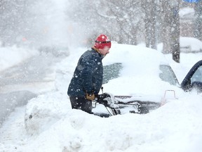 Guy Dupuis uses his snowblower to help out a young woman who's car was stuck in the snow on First Avenue during Tuesday's record snowfall. Julie Oliver