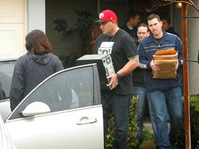 FBI and Homeland Security investigators carry a computer tower and manila envelopes from the Corona, Calif.,  home of Syed Raheel Farook while executing a search warrant at the home on Thursday, Feb. 18, 2016. FBI agents on Thursday were searching the California townhome of the brother of one of the shooters in the San Bernardino terror attack. Syed Raheel Farook is a Navy veteran who earned medals for fighting global terrorism. (Stan Lim /The Press-Enterprise via AP)