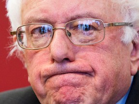 Listening journalists and television cameras are reflected in the glasses of Democratic presidential candidate, Sen. Bernie Sanders, I-Vt. as he meets with leaders of nine historic civil rights groups, at the National Urban League Washington Bureau in Washington on Thursday Feb. 18, 2016. (AP Photo/Jacquelyn Martin)