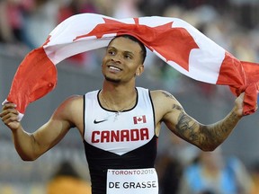 Andre De Grasse holds a Canadian flag after winning the gold medal in the men’s 100-metres during the athletics competition at the 2015 Pan Am Games Wednesday, July 22, 2015. (THE CANADIAN PRESS/Frank Gunn)