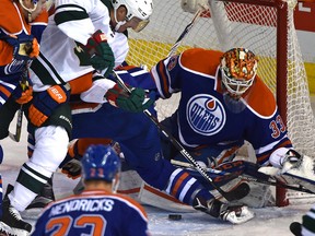Oilers goalie Cam Talbot battles Wild forward Ryan Carter for the puck during first-period action at Rexall Place on Thursday. (Ed Kaiser)
