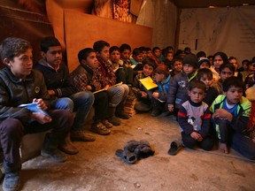 In this Wednesday, Jan. 27, 2016 photo, Syrian refugee children sit on the ground as they listen to their teacher inside a tent that has been turned into a makeshift school, at a Syrian refugee camp in Qab Elias, a village in the Bekaa Valley, Lebanon. (AP Photo/Bilal Hussein)