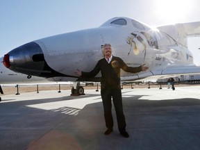 In this Sept. 25, 2013, file photo, British entrepreneur Richard Branson poses with the first SpaceShipTwo at a Virgin Galactic hangar at Mojave Air and Space Port in Mojave, Calif. Virgin Galactic will roll out a new copy of its space tourism rocket Friday, Feb. 19, 2016, as it prepares to resume flight testing for the first time since a 2014 accident destroyed the original and killed one of its two pilots.  (AP Photo/Reed Saxon, File)
