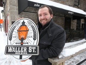 George Bush from Waller Street Brewing Co. poses for a photo with a new company sign in Ottawa Wednesday Feb 17, 2016. The company sign was stolen a couple weeks ago and Broadhead Brewing Co. created a new sign for them.