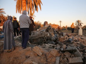 In this Friday, Feb. 19, 2016 photo, people gather after an air strike on a house and training camp belonging to the Islamic State group, west of Sabratha, Libya. (AP Photo/Mohamed Ben Khalifa)