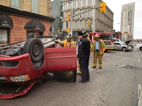 Const. Antoni Uchmanowicz talks to firefighters at the scene of a Sunday morning rollover at King and Richmond streets in London. Mike Hensen/The London Free Press/Postmedia Network