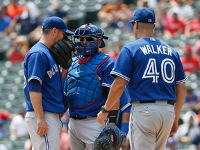 Toronto Blue Jays starting pitcher Marco Estrada, left, and catcher Dioner Navarro talk on the mound as pitching coach Pete Walker pays a visit in the first inning against the Texas Rangers in Arlington on Aug. 27, 2015. (AP Photo/Tony Gutierrez)