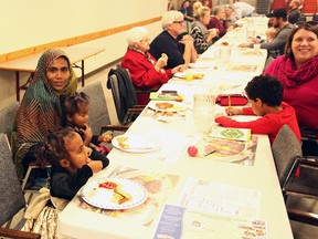 Ambiya and her two daughters eating food at their Welcome to Seaforth Benefit Breakfast on February 21. (Shaun Gregory/Huron Expositor)