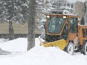 A sidewalk plow came along at a most inopportune time as residents were shovelling out a driveway on Portsmouth Avenue in Kingston, Ont. Homeowners were out all morning trying to keep up with the snowfall. (MICHAEL LEA\THE WHIG STANDARD)