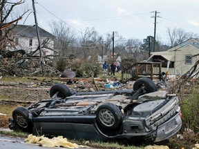 An overturned car rest on a highway next to the foundation of a mobile home that was throw across the highway by a deadly storm that swept through Waverly, Va., Wednesday, Feb. 24, 2016. (AP Photo/Steve Helber)