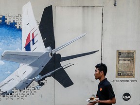 In this Tuesday, Feb. 23, 2016 photo, a waiter walks past a mural of flight MH370 in Shah Alam outside Kuala Lumpur, Malaysia.  (AP Photo/Joshua Paul)