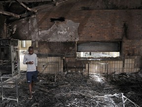 A student walks through the remains of the Science Center at the University of the North-West University in Mahikeng, South Africa, (also known as Mafikeng) Thursday, Feb. 25, 2016.  Protesting students burned down several buildings on the campus Wednesday forcing the evacuation and indefinite closure until further notice spokesman said Thursday. (AP Photo)