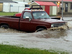 A motorist is seen bumper deep in water on June 19, 2015 while travelling along a road in Grande Prairie, Alta. (Jocelyn Turner/Postmedia Network)