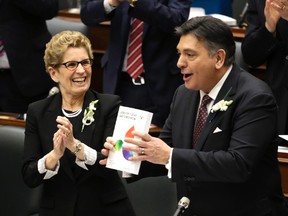 Ontario Minister of Finance Charles Sousa holds up the 2016 Budget with Premier Kathleen Wynne looking on at Queen's Park in Toronto Thursday, February 25, 2016. (Craig Robertson/Toronto Sun)
