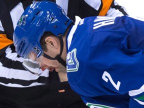 Vancouver Canucks defenceman Dan Hamhuis is helped off the ice by referee Ian Walsh after being struck in the mouth by the puck during third-period NHL action against the New York Rangers in Vancouver on Dec. 9, 2015. (THE CANADIAN PRESS/Darryl Dyck)
