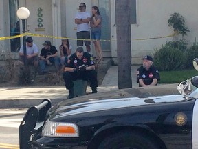 Members of the Klu Klux Klan involved in a stabbing incident sit on the curb behind a police cruiser near a planned KKK rally in Anaheim, California February 27, 2016. At least three people were stabbed on Saturday and one of them was critically wounded in a scuffle between members of the Klan and counter protesters near the planned rally, police said.  REUTERS/Tori Richards