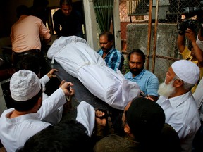 People carry the body of Indian man Hasnain Warekar, after autopsy from a hospital in Thane, outskirts of Mumbai, India, Sunday, Feb. 28, 2016. Warekar, 35 fatally stabbed 14 members of his family, including seven children, early Sunday before hanging himself, police said. (AP Photo/Rajanish Kakade)