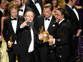 Emmanuel Lubezki, from left, Leonardo DiCaprio, and Alejandro G. Inarritu, all of whom picked up awards for The Revenant, take a selfie on stage at the conclusion of the show at the Oscars on Sunday, Feb. 28, 2016, at the Dolby Theatre in Los Angeles. Many who worked on the film gathered at Flames Central to watch the Oscars.(Photo by Chris Pizzello/Invision/AP)