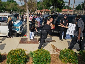 This photo provided by OC Weekly shows counter-protesters scuffling with a KKK member as he stabs an attacking protester, center, as members of the KKK try to start an anti-immigration rally at Pearson Park in Anaheim on Saturday, Feb. 27, 2016. Three people were stabbed Saturday, one critically, after a small group of Ku Klux Klan members staging an anti-immigrant rally clashed with a larger gathering of counter-protesters, police said. (Eric Hood/OC Weekly via AP) MANDATORY CREDIT