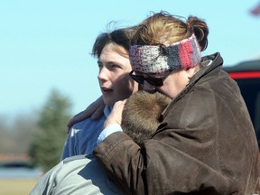A child is comforted Monday, Feb. 29, 2016, in Madison Township, Ohio after a school shooting at Madison Local Schools. An Ohio sheriff says a 14-year-old suspect is in custody. (Marshall Gorby/Dayton Daily News via AP)