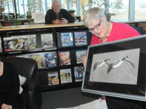 Ernst Kuglin/The Intelligencer
Children’s Librarian Rosemary Kirby looks at a framed printed presented to her by Quinte West Public library board chair Judy Vanleeven, during a retirement party held Friday. Kirby spent 29-years working at the library.