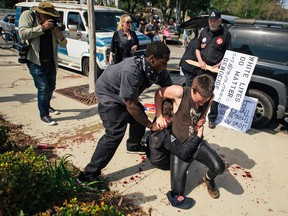 This photo provided by OC Weekly shows counter-protesters scuffling with a KKK member, on the ground, as he stabs an attacking protester, during an anti-immigration rally at Pearson Park in Anaheim on Saturday, Feb. 27, 2016. Three people were stabbed Saturday, one critically, after a small group of Ku Klux Klan members staging an anti-immigrant rally clashed with a larger gathering of counter-protesters, police said. (Eric Hood/OC Weekly via AP)
