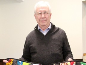 Pat McGill poses with some quilted bags stitched by Ugandan women that he's helping sell in Canada. It's part of his work with the charity Soft Power. (Tyler Kula/Sarnia Observer/Postmedia Network)