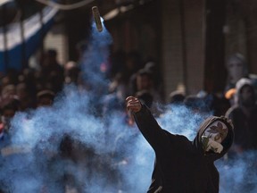 A Kashmiri Muslim protester throws back an exploded tear gas shell at Indian policemen during a protest in Srinagar, Indian controlled Kashmir, Friday, Feb. 26, 2016. Government forces fired tear gas and pellet guns to stop hundreds of rock-throwing Kashmiri youths in Indian-controlled Kashmir after separatists called for protests against  the arrest of a Delhi University lecturer, S.A.R. Geelani, and student leaders of the Jawaharlal Nehru University (JNU) on charges of sedition for raising anti-India slogans. Geelani also allegedly criticized the 2013 hanging of Afzal Guru, convicted of attacking the Indian Parliament. (AP Photo/Dar Yasin)