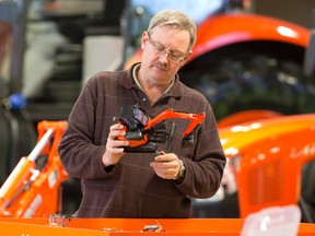 John Rex screws a tether to the bottom of a toy digger as he sets up a sandbox Tuesday at the Kubota booth at the London Farm Show at the Western Fair District. More than 14,000 people are expected to visit the three-day show. (CRAIG GLOVER, The London Free Press)