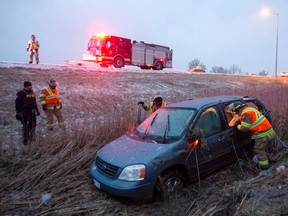 Firefighters search a van for its driver's identification after it rolled into a ditch on Highway 402 near Colonel Talbot Road in London on Tuesday. The driver of the minivan wasn't injured.  Craig Glover/The London Free Press/Postmedia Network