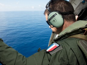 A French military transport crew member inspects the Indian Ocean during a search mission for Malaysia Airlines flight MH370 along the coast near Saint-Andre on the French island of Reunion, in this handout picture provided by the French Army on August 9, 2015. REUTERS/Patrick Becot/ECPAD/Handout via Reuters