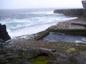 In this Sept. 13, 2015 photo, aaves pound the naturally formed pool known as the Serpent's Lair on the island of Inishmore in Ireland. This pool has twice been the site of the Red Bull Cliff Diving tour. (Michelle Locke via AP)