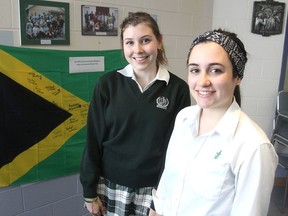 Standing in front of a Jamaican flag at their school in Kingston, Holly Hebert, left, and Anna Stafford were among a group of students to go on a humanitarian mission to the island last month. (Michael Lea/The Whig-Standard)