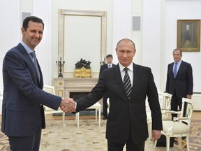 Russian President Vladimir Putin (R) shakes hands with Syrian President Bashar al-Assad during a meeting at the Kremlin in Moscow, Russia, in this October 20, 2015 file photo. To match Insight REUTERS/Alexei Druzhinin/RIA Novosti/Kremlin/ Files