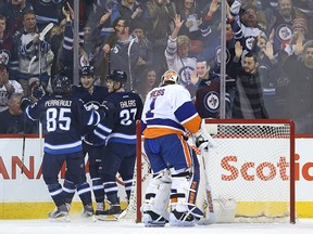 Jets centre Mark Scheifele (centre) celebrates his first-period, power-play goal past New York Islanders goaltender Thomas Greiss with Mathieu Perreault (left) and Nikolaj Ehlers on Thursday. (Kevin King/Winnipeg Sun/Postmedia Network)