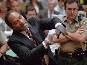 In this June 15, 1995, file photo, murder defendant, O.J. Simpson grimaces as he tries on one of the leather gloves prosecutors say he wore the night his ex-wife Nicole Brown Simpson and Ron Goldman were murdered, during the Simpson double-murder trial in Los Angeles. (Sam Mircovich via AP, Pool, File)
