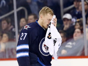 Winnipeg Jets left wing Nikolaj Ehlers (27) leaves the ice after he is hit in the face by the puck during the overtime period against the New York Islanders at the MTS Centre Thursday. Bruce Fedyck-USA TODAY Sports