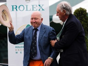 Tennis Hall of Fame member Bud Collins (left) is helped up by fellow Tennis Hall of Famer Owen Davidson as he greets the crowd gathered for the Tennis Hall of Fame Induction Ceremony in Newport, Rhode Island on July 13, 2013. Collins, who covered more than half a century of tennis championships, died on Friday at age 86. (Jessica Rinaldi/Reuters/Files)