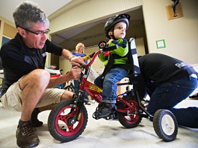 Bicycle mechanic Jonathan Woelder, left, makes adjustments to a tricycle ridden by Charlie Ross, 3, during a bicycle fitting day for children with special needs put on by You Can Ride 2 at the Robin Hood Children and Youth Centre in Sherwood Park, Alta., on Saturday, April 11, 2015. Codie McLachlan/Postmedia Network