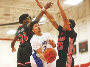 Henry Carr’s Carlo Dubria, going under Jean Vanier’s Rubben Kasongo (23) and Chris D’Souza (15) in the TDCAA final last week, will try to lead the top-ranked Crusaders over the hump at the OFSAA basketball tourney this week in Windsor. (JACK BOLAND, Toronto Sun)