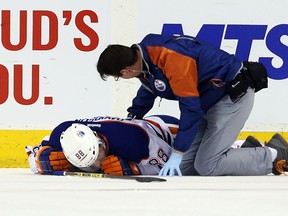 Edmonton Oilers defenceman Brandon Davidson is tended to by a team trainer after appearing to injure his left knee Sunday night against the Winnipeg Jets in the MTS Centre. Initial word from the team is it doesn’t look good for the young defenceman. (Bruce Fedyck/USA Today Sports)