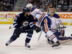 Winnipeg Jets' Mathieu Perreault (85) battles with Edmonton Oilers' Adam Clendening (27) in front of Oilers' goalie Cam Talbot (33) during second period NHL hockey action, in Winnipeg on Sunday, Mar. 6, 2016.