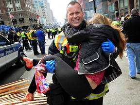 In this April 15, 2013 file photo, Boston Firefighter James Plourde carries Victoria McGrath from the scene after a bombing near the Boston Marathon finish line. (AP Photo/MetroWest Daily News, Ken McGagh, File)
