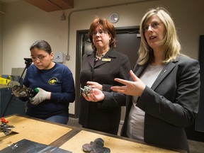 Tessa Minde uses metal cutters to create a metal rose as JudyLynn Archer, President and CEO, Women Building Futures and Status of Women Minister, Stephanie McLean tour the metal shop at the Woman Building Futures Society on March 7, 2016.