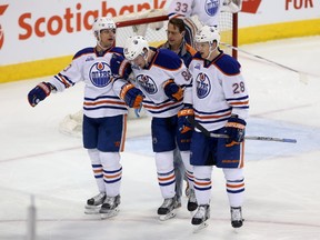 Brandon Davidson is helped off the ice by teammates Matt Hendricks, left, and Lauri Korpikoski during Sunday's game against the Jets in Winnipeg. (Trevor Hagan, The Canadian Press)