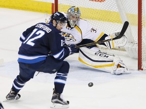 Mar 8, 2016; Winnipeg, Manitoba, CAN; Winnipeg Jets right wing Drew Stafford (12) looks to control a loose puck in front of Nashville Predators goalie Pekka Rinne (35) during the second period at the MTS Centre. Mandatory Credit: Bruce Fedyck-USA TODAY Sports