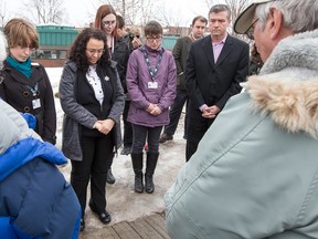 Members of the Pine Grove Bible Church in Beacon Hill say prayers with Councillor Tim Tierney (R) in attendance during a morning vigil at the corner of Ogilvie Road and Jasmine Crescent, near the spot where a young man was gunned down on Tuesday evening. WAYNE CUDDINGTON