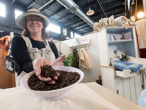 Elizabeth deLange digs her hand into a bowl of flax seed, the filler used in her handmade pillows at Harvest Pillows in the Western Fair Farmers' and Artisans' Market in London. (CRAIG GLOVER, The London Free Press)